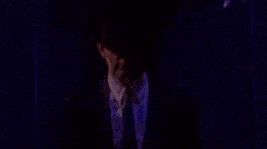 a man in a suit and tie is standing in front of a purple curtain