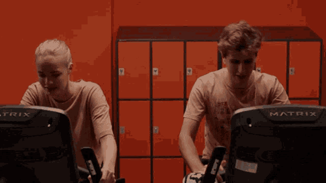 a man and a woman are riding a matrix bike in a gym