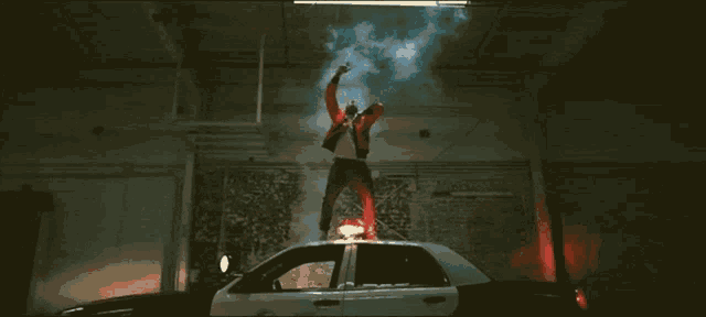 a man stands on top of a police car with smoke coming out of it