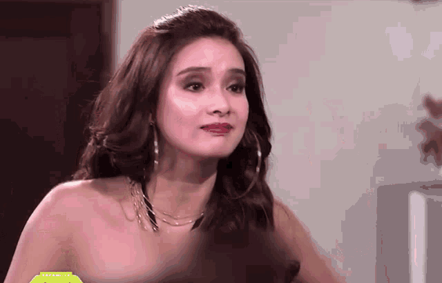 a woman without a shirt is wearing hoop earrings and a necklace ..
