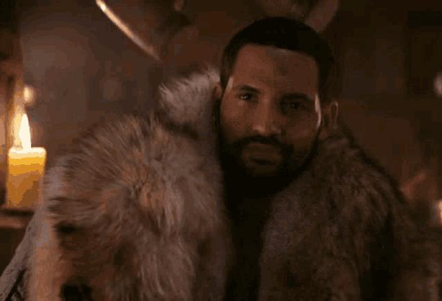a man wearing a fur coat is holding a knife in his hand .