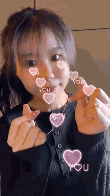 a girl is making a heart shape with her hands and the word you is surrounded by pink hearts