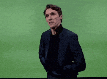 a man in a suit and black shirt is dancing on a green screen .