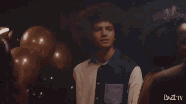 a man is dancing in front of balloons and the word brat tv is on the bottom of the image