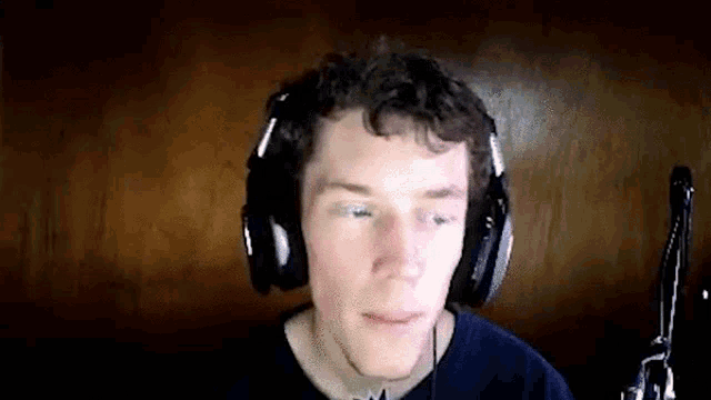 a man wearing headphones is looking at the camera and making a funny face .