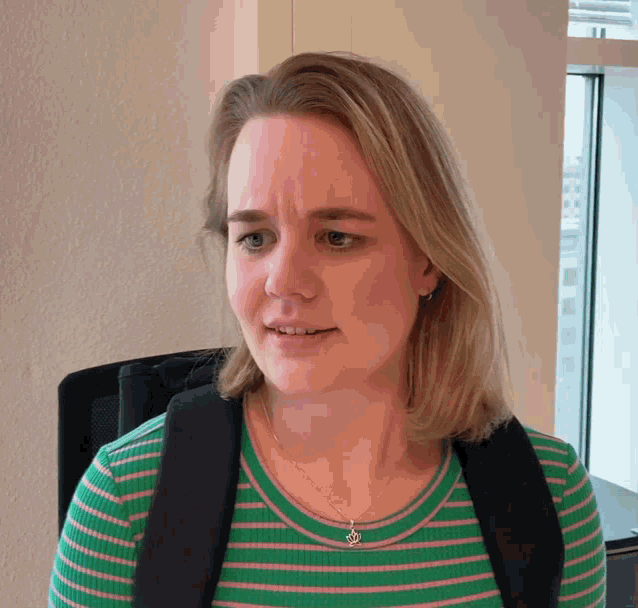 a woman wearing a green and pink striped shirt with a necklace that says ' i love you ' on it