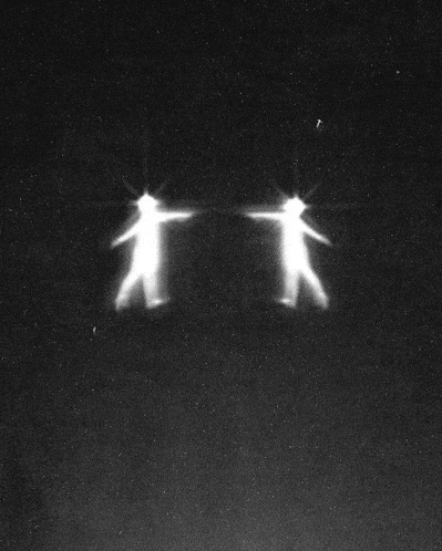 a black and white photo of two people standing next to each other with their arms outstretched