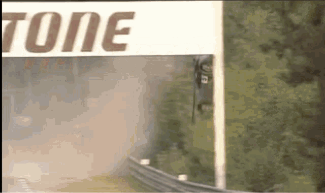 a race car is going down a track in front of a sign that says ' tone '