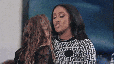 a woman in a fendi sweater kisses another woman