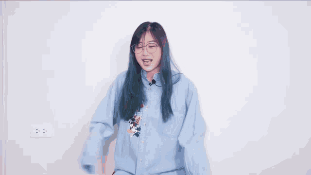 a girl wearing glasses and a blue shirt is dancing