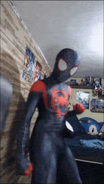 a man in a spiderman costume stands in a bedroom