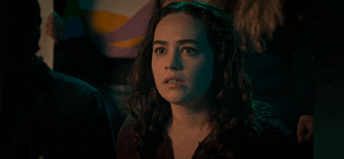 a woman with a surprised look on her face is standing in a dark room