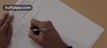 a person is holding a pen and writing on a piece of paper .