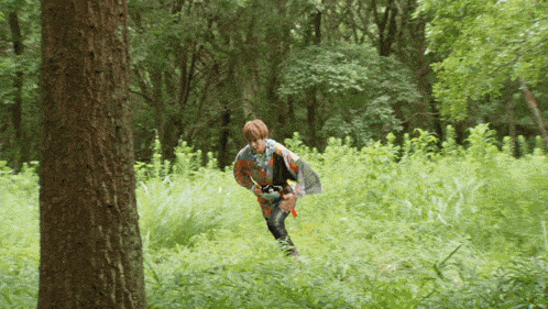 a person is walking through a lush green forest with trees in the background