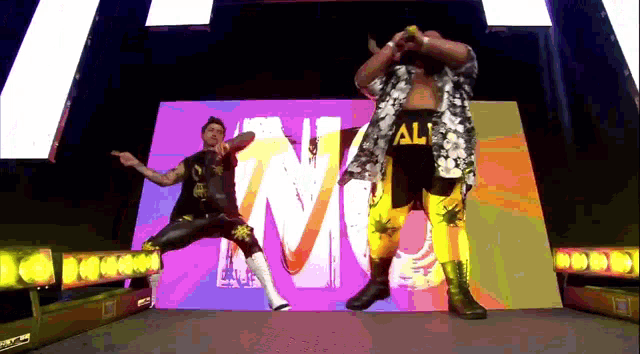 two wrestlers are dancing in front of a screen that says nm