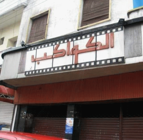 a red car is parked in front of a building with a sign that says ' lk ' on it .