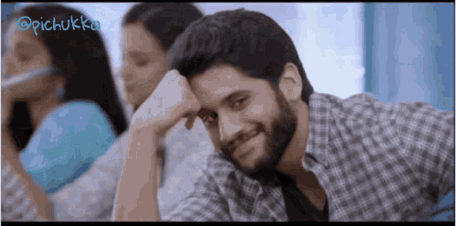 a man with a beard is smiling with his hand on his head
