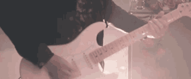 a man is playing a white electric guitar in a room .