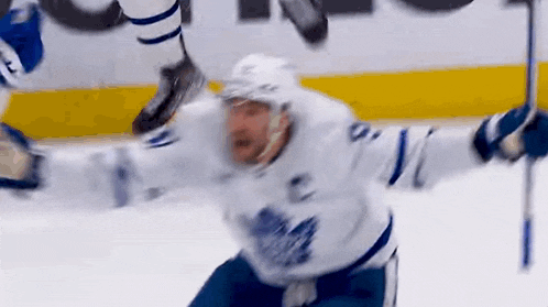 a hockey player is falling on the ice after being hit by a puck during a game .