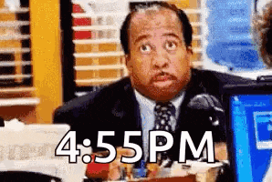 a man in a suit and tie is sitting at a desk with 4:55 pm written on the bottom .