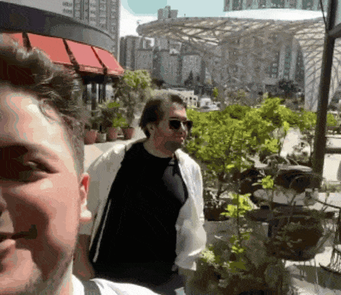a man wearing sunglasses and a black shirt is standing next to another man
