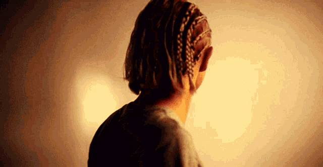 a person with braids in their hair is standing in front of a wall .