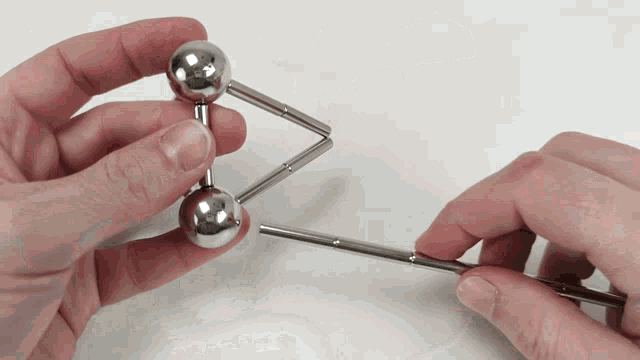 a person is holding two metal balls and a metal stick
