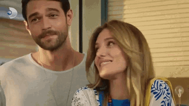a man and a woman are smiling and looking at each other .