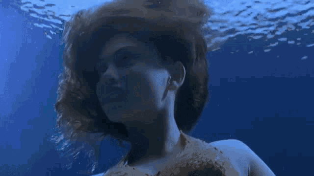 a woman is swimming in the ocean and smiling at the camera