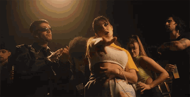 a group of people are dancing and one of them is pointing at the camera