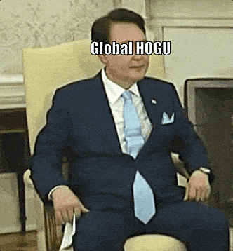 a man in a suit and tie is sitting in a chair with his legs crossed and the words global hogu on his face