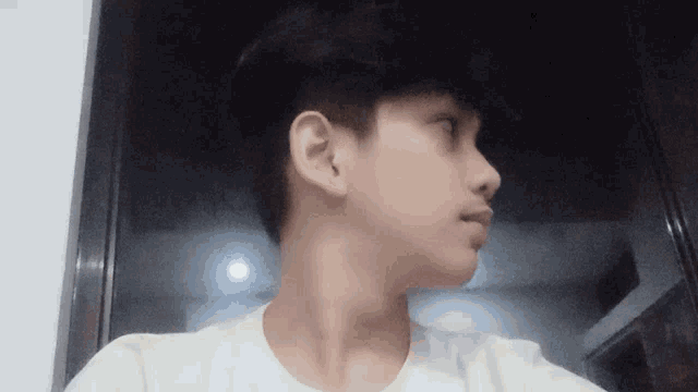 a young man in a white t-shirt looks at the camera