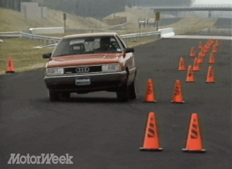 a red audi car is driving down a road with orange cones