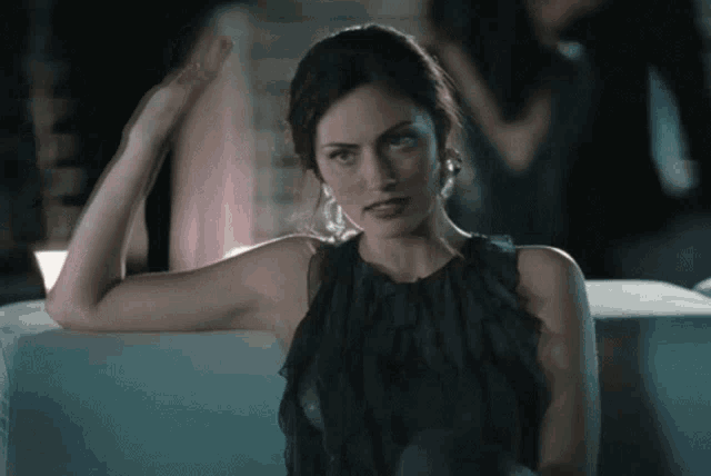 a woman in a black dress sits on a couch