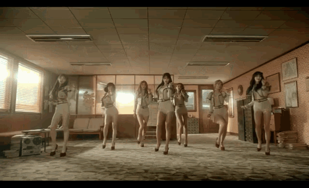 a group of women are dancing in a room with a ceiling fan