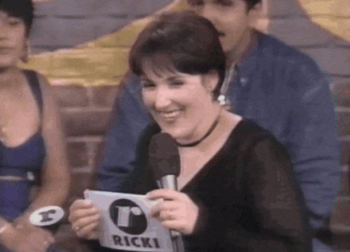 a woman is holding a sign that says ricki on it