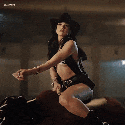 a woman wearing a cowboy hat and shorts is riding a bull .