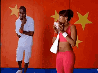 a man and a woman are standing in front of a red wall with yellow stars .