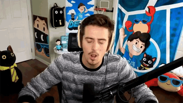 a man wearing headphones is sitting in front of a microphone in a room with a poster on the wall that says def