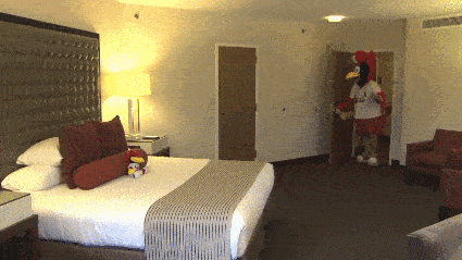 a room with a bed and a mascot wearing a shirt that says texas