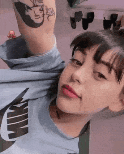 a girl with a tattoo on her arm is wearing a blue nike shirt