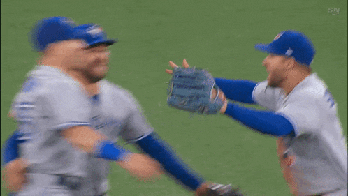 three baseball players are hugging each other on a field .