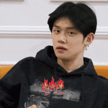 a young man wearing a black hoodie with flames on the front