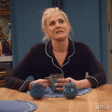 a woman sits at a table with a netflix logo on the bottom