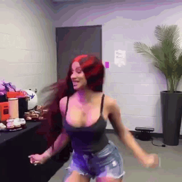 a woman with red hair is dancing in a room with a plant in the background .