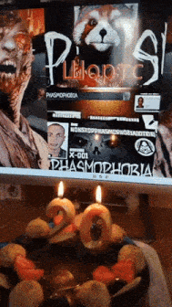 a birthday cake with candles in front of a computer screen that says phasmophobia on it