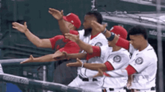 a group of baseball players are standing next to each other with their arms outstretched .
