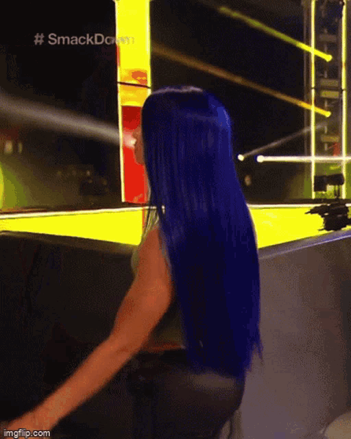 a woman with blue hair is sitting in front of a yellow sign that says smackdown .