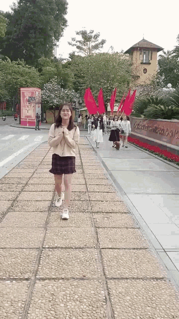 a woman walking down a sidewalk with red flags in front of a building that says ' trung quoc ' on it