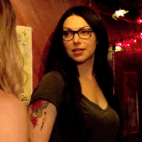 a woman with glasses and a tattoo on her arm is standing next to another woman